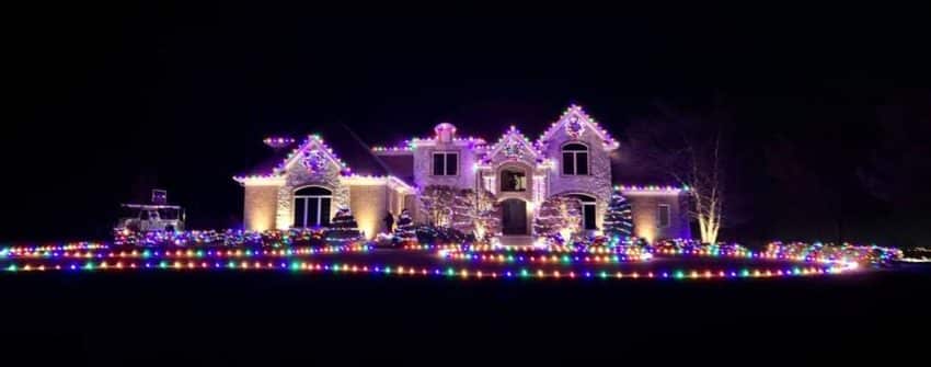 Happy Indianapolis family enjoying their professionally installed outdoor lighting display during the holidays by Indy Christmas Lights Pros.